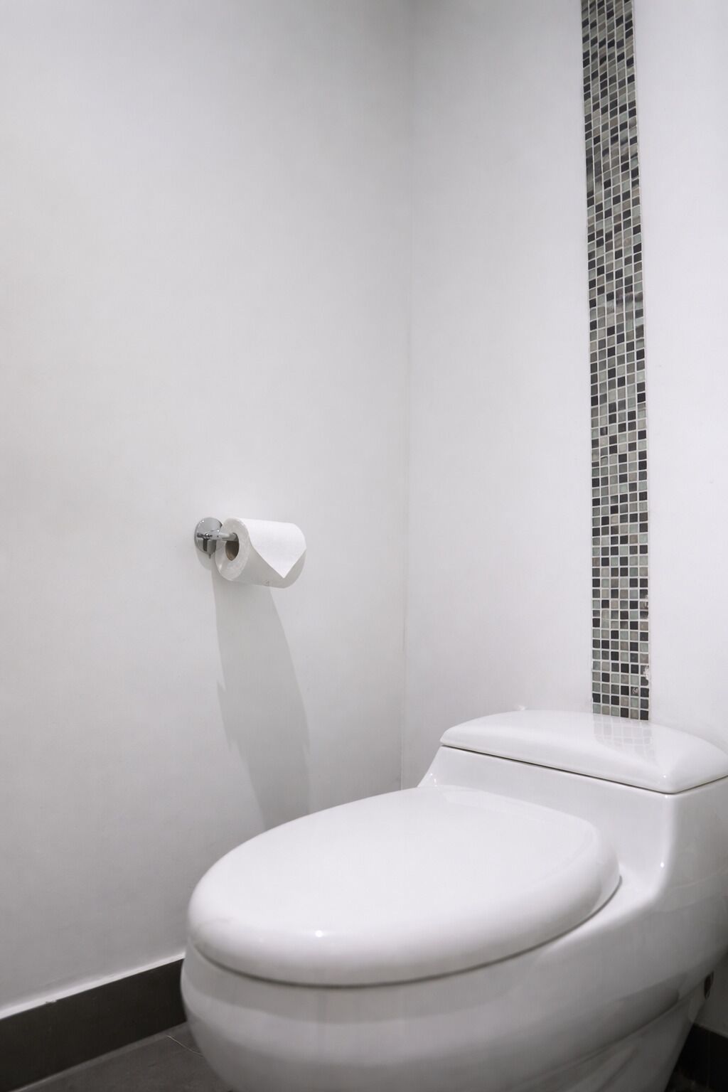 Un vàter blanc amb una columna d'azulejos mosaics al bany.