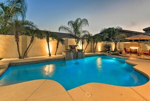 Ein Pool mit gewölbter Kante, umgeben von Palmen und einer Steinmauer.