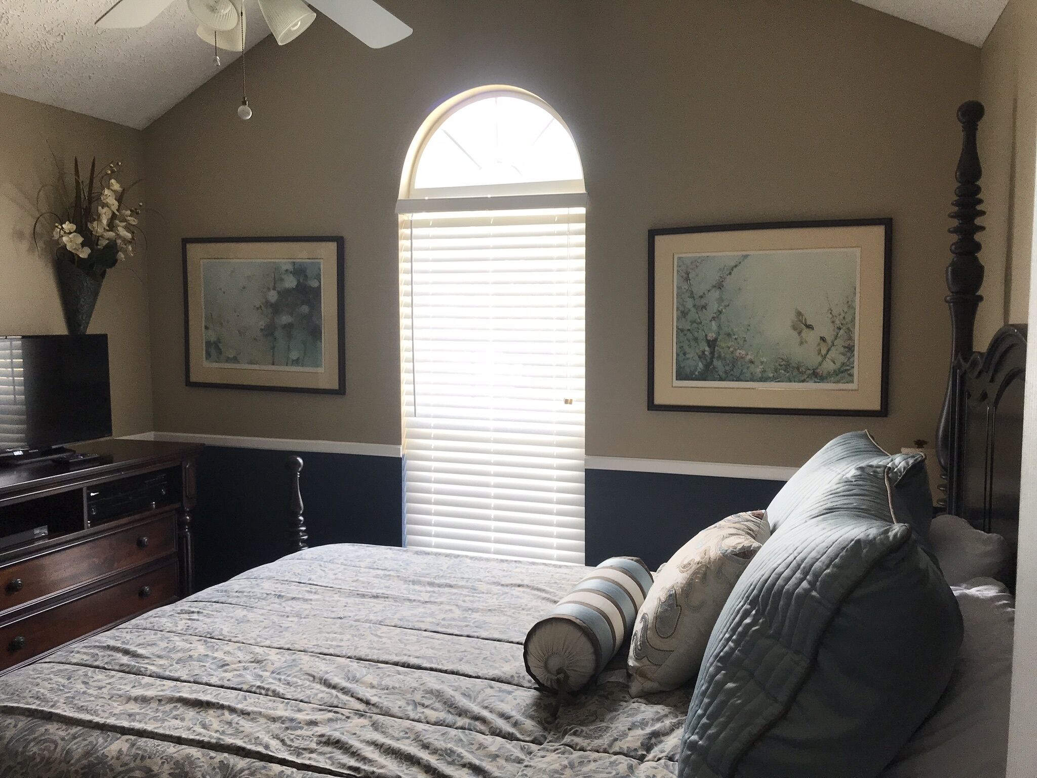 Une chambre à coucher avec un lit, une commode et deux tableaux encadrés accrochés au mur.