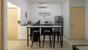 Una cocina compacta con una isla central, taburetes de bar y una nube de palabras en la pared.