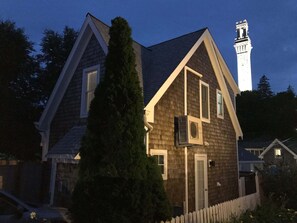 Una casa de dos pisos con un techo empinado, una chimenea y una cerca blanca de piquetes.