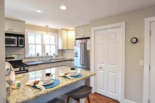A kitchen with white cabinets, a stainless steel refrigerator, a microwave, and a stove. - 4 min Walk to Commercial Street and Beach! (Provincetown)