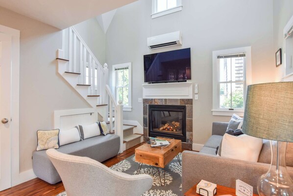 A living room with a fireplace, a television, and a staircase. - 4 min Walk to Commercial Street and Beach! (Provincetown)