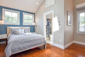 A bedroom with a bed, two bedside tables, a window, a door, and a wall-mounted air conditioning unit. - 4 min Walk to Commercial Street and Beach! (Provincetown)