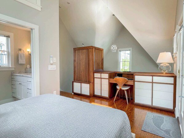 Un dormitorio con cama, escritorio, silla, armario y ventana.