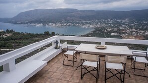 A terrace with a table and chairs overlooking a coastal town and mountains. - Architect designed Cretan Sea Vista (Chania)