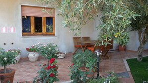 A patio area with potted plants, a wooden table and chairs, and a window with blinds. - House in Teulada for 4 people a few minutes from the beautiful beaches  (Teulada)