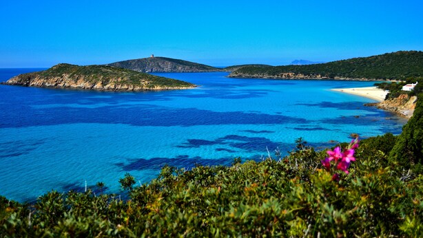A coastal landscape with clear blue waters, a hilltop structure, and a beach. - House in Teulada for 4 people a few minutes from the beautiful beaches  (Teulada)