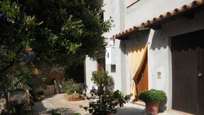 A courtyard with potted plants, a tiled roof, and a wooden door. - House in Teulada for 4 people a few minutes from the beautiful beaches  (Teulada)