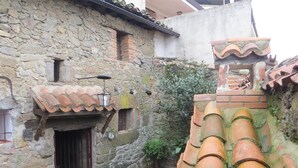 A stone building with a tiled roof, a small door, and a window. - Your Village House Tiétar Valley (La Iglesuela)