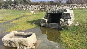 A stone structure with a small pond in front, surrounded by grass and a stone wall in the background. - Your Village House Tiétar Valley (La Iglesuela)