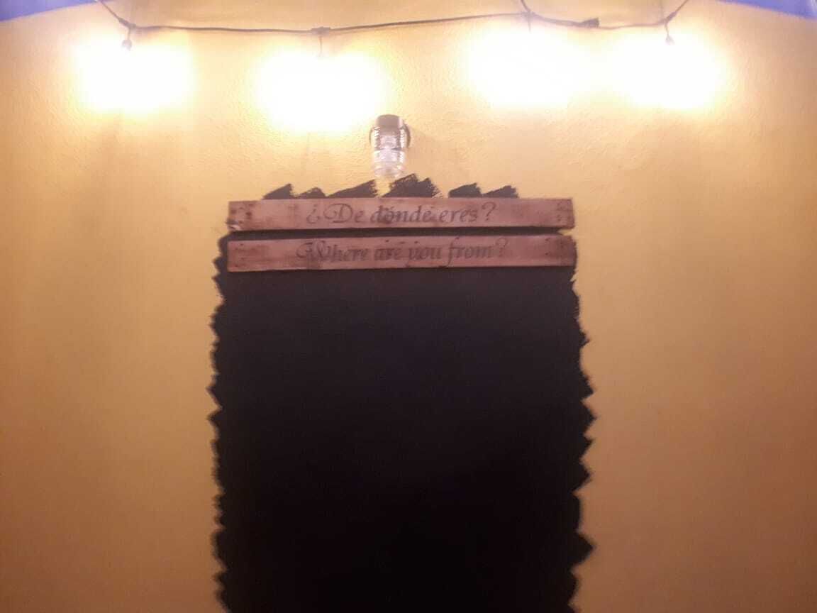 A wall with a wooden sign that reads "¿De dónde eres?" and "Where are you from?" with a water bottle hanging above it.