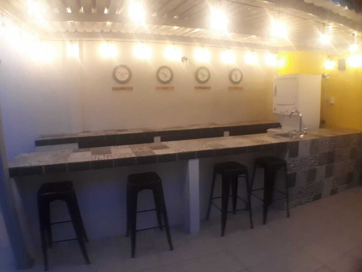 Un espace bar avec un comptoir, quatre tabourets et des horloges murales.