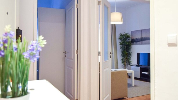 A hallway leading to a living area with a sofa, a TV, and a lamp. - Family House in central Lisbon (Lisboa)