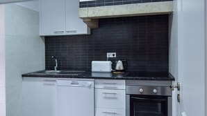 A compact kitchen with a dishwasher, oven, toaster, and kettle. - Family House in central Lisbon (Lisboa)