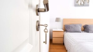 A bedroom with a bed, nightstand, and wall-mounted lamp. - Family House in central Lisbon (Lisboa)