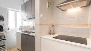 A modern kitchen with white cabinets, a stainless steel range hood, and a built-in oven. - Casa Sanches (Cascais)