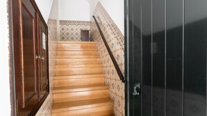 A wooden staircase with patterned walls and a dark door. - Casa Sanches (Cascais)