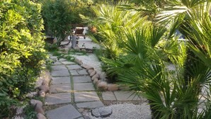 A garden pathway with stone tiles and surrounding greenery.