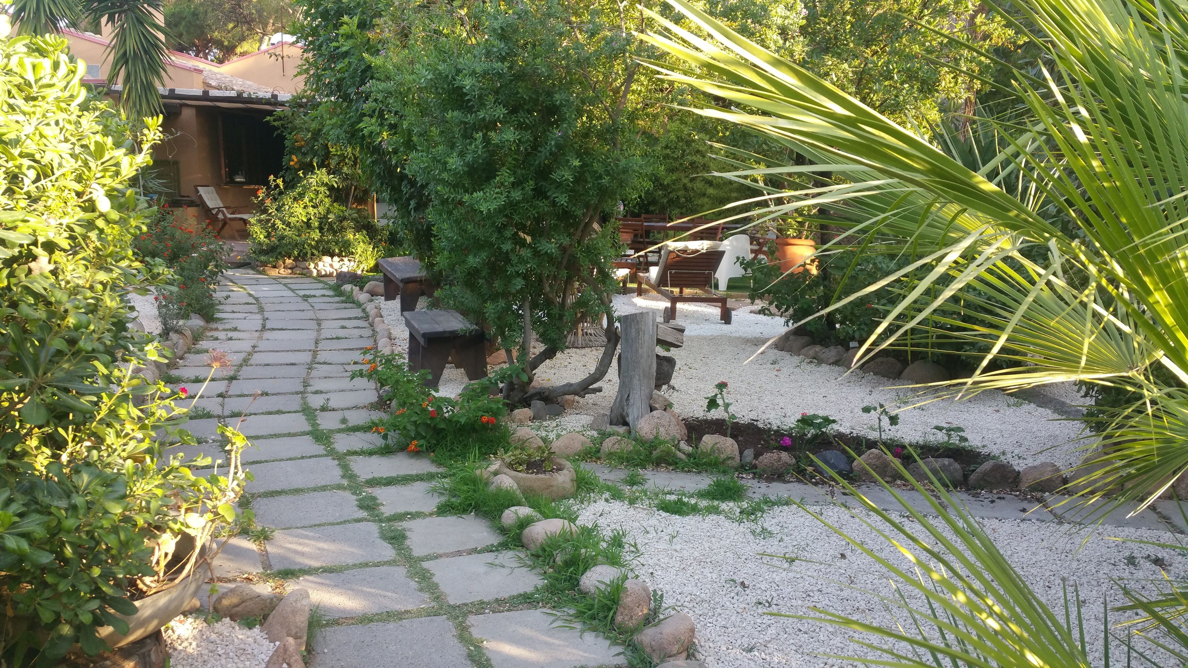 Un sentier de jardin pavé de dalles de pierre, bordé de différentes plantes et de rochers.