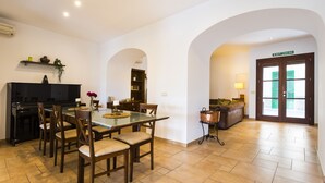 A dining area with a piano, a glass table, and chairs. There is a bookshelf and a door labeled "EXIT SALIDA". - Ca na Patrona, viewpoint to Capdepera Castle. With pool and bbq (ETV / 8903) (Capdepera)