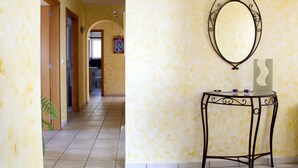 A hallway with a tiled floor, a wooden door, and a small table with a mirror. - Villa with panoramic views of the sea and the Rock of Ifach, with private pool. (Calpe)