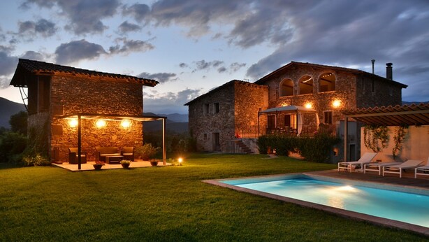 A stone house with a pool and outdoor seating area.