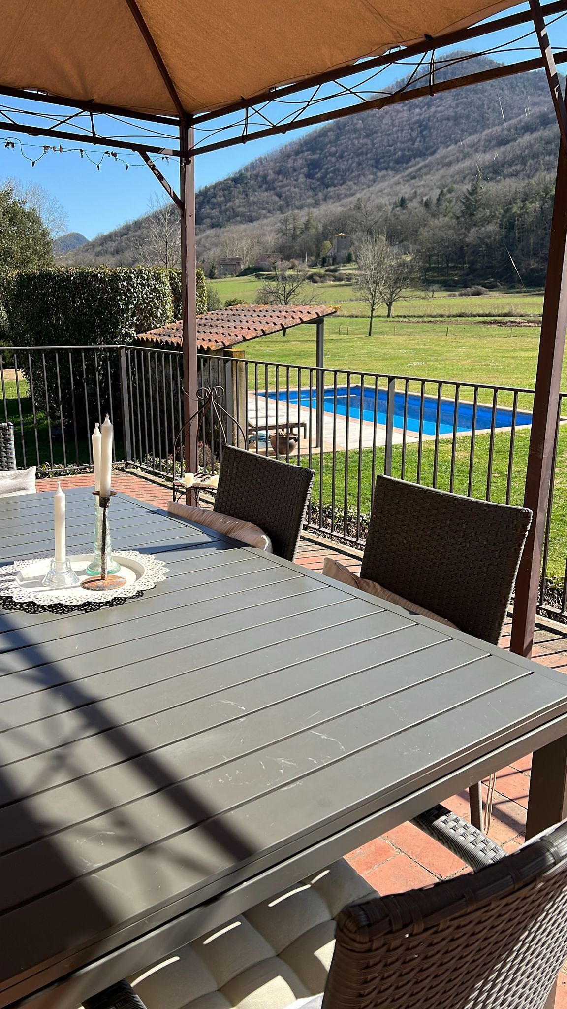 Een terras buiten met een tafel en stoelen, met uitzicht op een zwembad en een prachtig landschap.