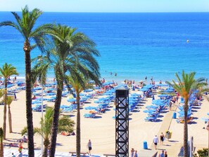 A beach with palm trees, sun loungers, and a lifeguard tower.