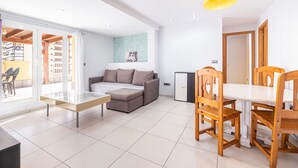 A modern living room with a sofa, a dining table with chairs, and a small cabinet. - Atico Ancla Penthouse (Benidorm)