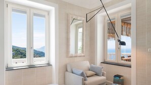A bedroom with a bed, a sofa, a small table, and a view of the sea. - Casa Mariavittoria - My Rental Homes (Massalubrense)
