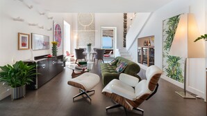 A modern living room with a sofa, chairs, a dining area, and a staircase leading to an upper level. - Casa Mariavittoria - My Rental Homes (Massalubrense)