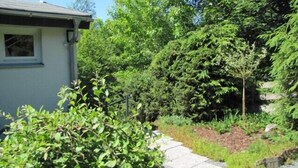 Un jardin résidentiel agrémenté d’un chemin pavé, de divers arbustes et d’arbres.