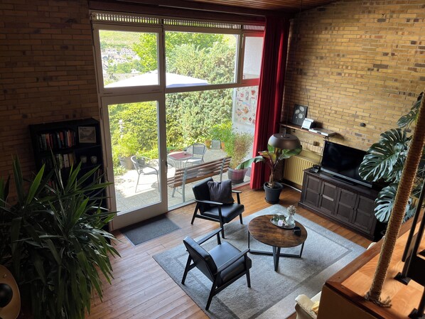 A spacious living room with a large sliding glass door leading to a patio, a wooden coffee table, a sofa, and a TV on a wooden cabinet.