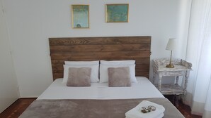 Un lit bien fait, avec une tête de lit en bois, deux oreillers et une serviette pliée posée sur le lit.