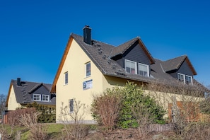 A residential building with a sloped roof, multiple windows, and a chimney. - Modern vacation home in Korswandt on the lake with large garden and fireplace (Korswandt)