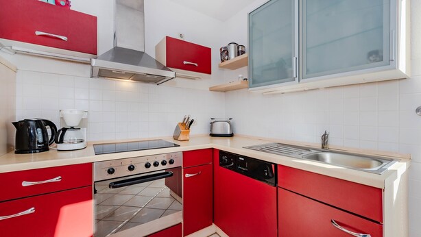 Une cuisine compacte équipée d’une cuisinière à gaz, d’un four, d’un lave-vaisselle et d’une fenêtre située au-dessus de l’évier.