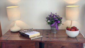 Un bureau en bois avec deux lampes, un livre, une plante en pot et un bol de fraises.