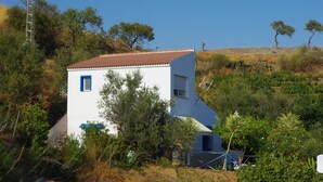 Un edifici blanc amb teulada vermella, envoltat de vegetació i arbres.