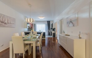 A modern dining area with a glass table, white chairs, and a pendant light.