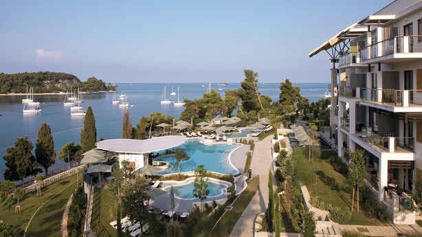 A resort with a pool, lounge chairs, and a view of the sea with boats. - Apartment Lella near the sea and city center 500 meters (Rovinj)