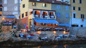 A coastal building with outdoor seating and a stone facade. - Apartment Lella near the sea and city center 500 meters (Rovinj)
