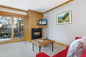 A cozy living room with a fireplace, a television, and a framed picture on the wall. - Vail Mtn Views and Rooftop Hot Tub LH314 (Vail)