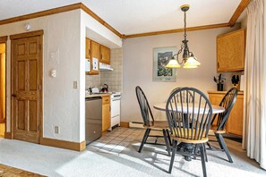 A kitchen with wooden cabinets, a stove, and a dining table with chairs. - Vail Mtn Views and Rooftop Hot Tub LH314 (Vail)
