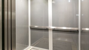 Un ascenseur moderne doté d’une main courante métallique et d’un panneau en verre.