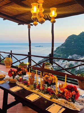 A table set for dining with a view of the sea and a mountain in the background.