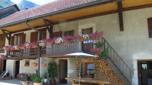 En traditionel schweizisk chalet med en træbalkon pyntet med blomster, en trætrap og et bord med bænke udenfor.
