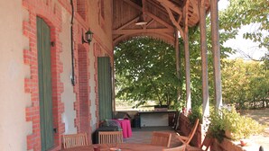 An outdoor patio with a wooden table and chairs, brick walls, and green shutters.