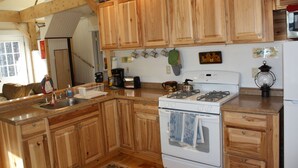 Une cuisine avec des meubles de rangement en bois, une cuisinière et un évier.