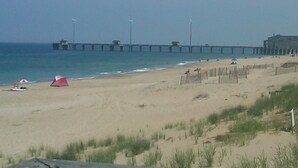 Une plage avec une jetée qui s’avance dans l’eau, des tentes et une clôture le long du rivage.
